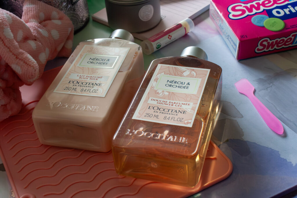 Product photo in flat layout of a Neroli & Orchidee bodywash and body milk with light pink and purple colours.