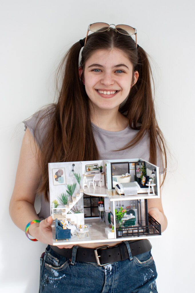 GIrl holding a model house against a white background.